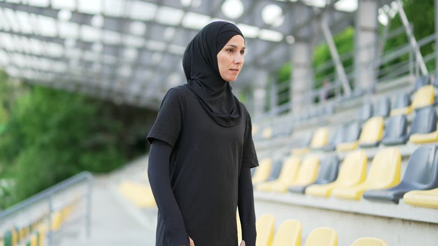 Young sporty muslim woman in hijab suffering from back pain, sports injury, muscle spasm in urban city stadium. Sad female having back flank ache, problem after exercise outside, massaging a sore spot Royalty-Free Stock Footage #1104949701