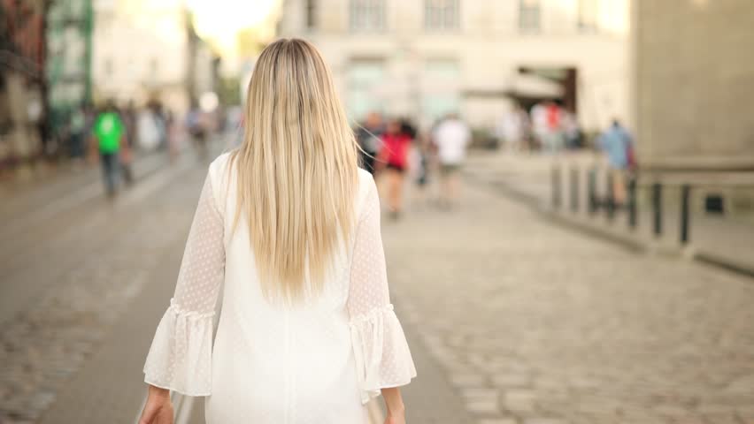 Beautiful woman with a magnificent golden hair. Fun happy young girl shake her head to make hair flying. Attractive young lady turns around and looks into the camera
