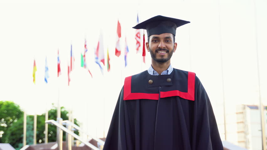 Cheerful indian guy in graduation costume showing his diploma and smiling at camera Royalty-Free Stock Footage #1104954239
