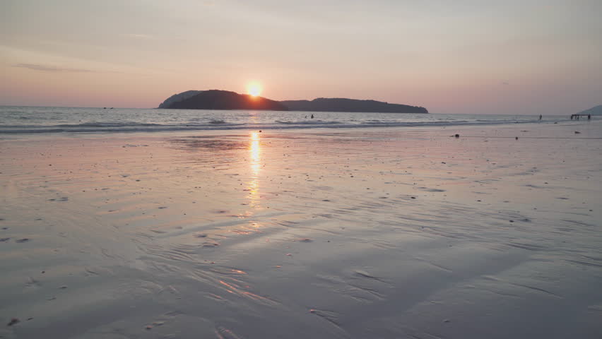 Awesome sunset view of Cenang Beach (Pantai Cenang) on Langkawi island in Malaysia. The sun is reflected in the sea and wet sand. Amazing seascape.