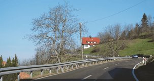 Clear skies grace a rural drive through the Black Forest. Houses, trees, and plant life outstretch toward the unrecognizable car journeying to a new destination.
