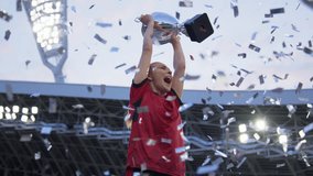 Portrait of Caucasian female soccer football player celebrating victory in the championship, lifting the trophy above her head in a huge stadium. Super slow motion, shot on RED cinema camera - Powered by Shutterstock - Get 15% off with code: PIKWIZARD15