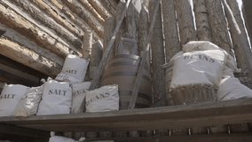 This video shows stacks of old time frontier food staples such as salt and beans, labeled in sacks.