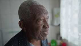 Contemplative senior African American man standing by window in kitchen. Close-up face of a black elderly male person with pensive thoughtful expression - Powered by Shutterstock - Get 15% off with code: PIKWIZARD15