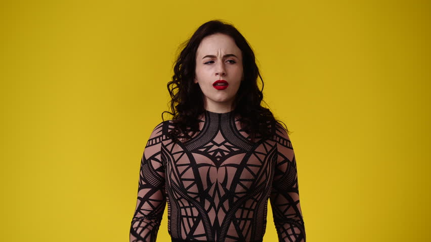 4k video of one girl with negative facial expression over yellow background.
