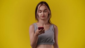 4k video of woman using her phone on yellow background.