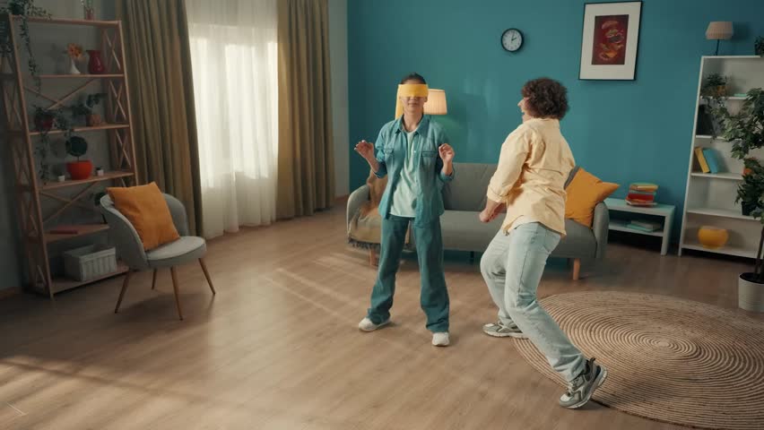 A young married couple spends time together, having fun. A couple is playing a game of blind man