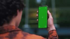 Closeup casual man making video call on smartphone in slow motion near modern office. Close up of businessman making video chat on green screen mobile phone. Male professional waving hand