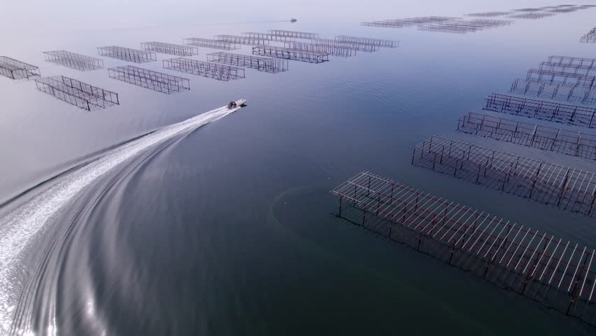 Aerial landscape shot of a motorboat sailing near cristal clear waters at Thau Lagoon in Sete, France.