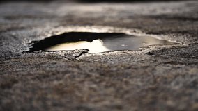 a dark reflection of the setting sun in a small puddle on a grey stone with bright yellow light and sharp surface texture - Powered by Shutterstock - Get 15% off with code: PIKWIZARD15