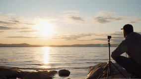 A young man shoots clouds in slow motion on an action camera on the shore of a lake. Place to insert.