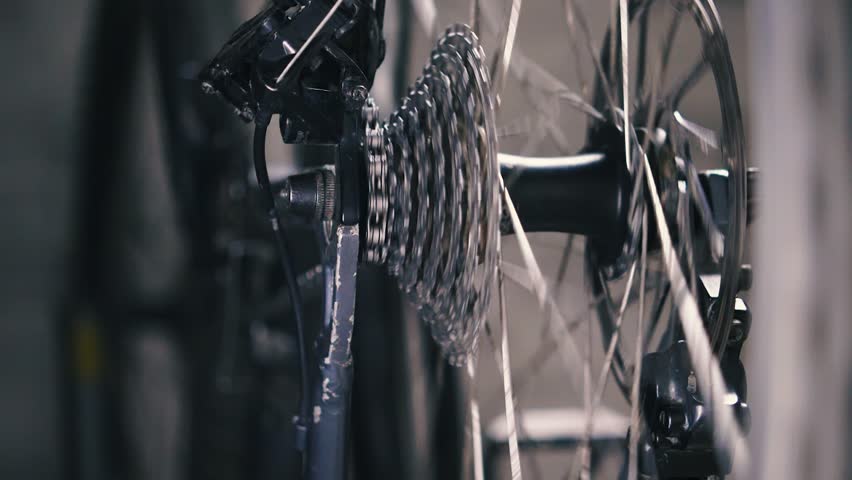 The bike's cassette and chain travel from small chainring to large chainring and back. The repairman's hand twists the pedals to check the rear derailleur. Close-up, slow motion Royalty-Free Stock Footage #1105000565