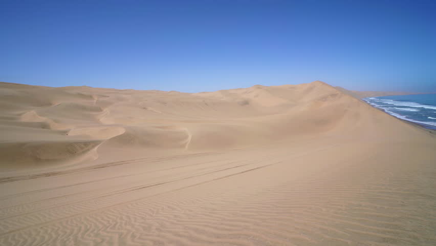 Pan on the Namib Desert meeting the Atlantic Ocean in the Skeleton Coast near Sandwich Harbour in Namibia, Africa. Royalty-Free Stock Footage #1105002831
