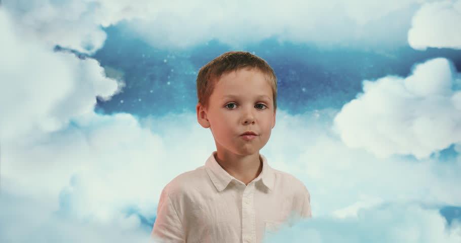 The small boy in blue skies blowing a big  bubble from bubble gum. Small boy chewing a gum and making giant bubble