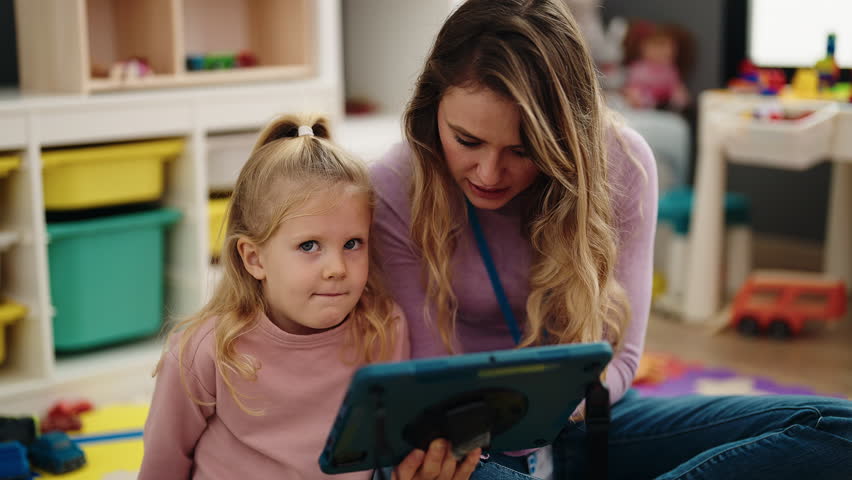 Woman and girl having lesson using touchpad at kindergarten