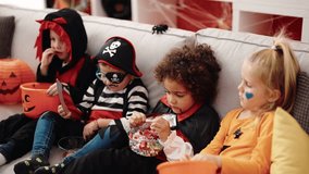 Group of kids wearing halloween costume eating candies at home - Powered by Shutterstock - Get 15% off with code: PIKWIZARD15