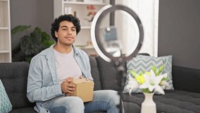 Young latin man unpacking joystick of cardboard box recording video tutorial at home