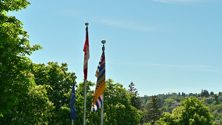 Unifying Spirits: Kamloops Logo, British Columbia, and Canada Flags Soaring in the Blue Sky