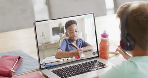 Caucasian boy using laptop for video call with african american school friend on screen. Communication, technology, school, learning and online education, digital composite video.