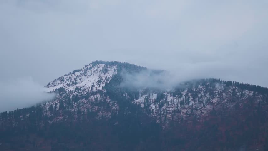Clouds above the snow covered Himalayan mountain peaks of Kullu valley during the winter storm at Manali in Himachal Pradesh, India. Clouds cover the peaks of mountains during storm in Himalayas.