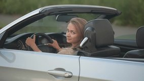 brown-haired woman driving a car. woman looking at the camera. car rental. slow motion video. High quality Full HD video recording