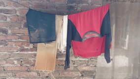 shabby and dirty clothes drying on the side of the brick house