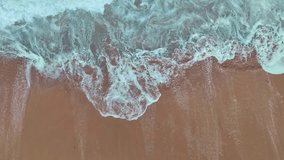 aerial top view the serene beauty of the scenery is breathtaking. 
The surface of the waves crashing on the sand breaks into beautiful patterns.
4K UHD 50 frame per second. Video slow motion Clip
