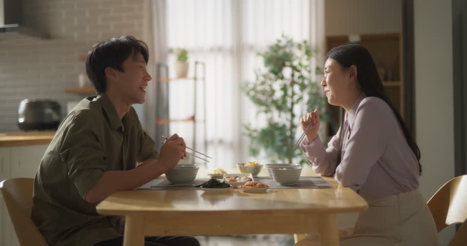South Korean Young Couple Cooked Food at Home and Eating Together in the Kitchen. Loving Man and Woman are Happy with Their Lifestyle, Enjoying Traditional Korean Dishes Fish, Vegetables and Kimchi Royalty-Free Stock Footage #1105013717