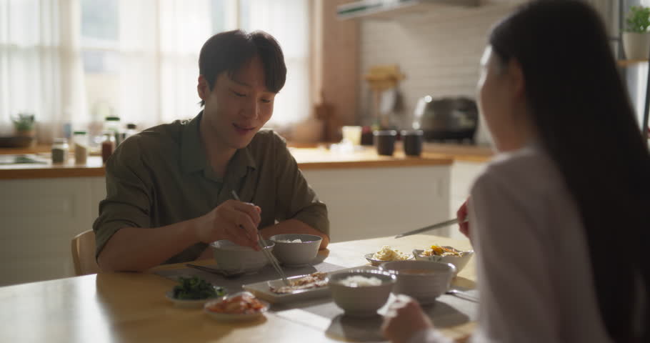Young Loving South Korean Couple Eating Homemade Tasty Food at Home and Having a Fun Chat. Asian Boyfriend and Girlfriend Enjoying Time Together, Feasting on Cooked Fish, Spicy Vegetable Soup and Rice | Shutterstock HD Video #1105013721