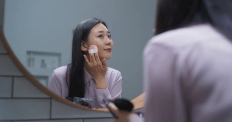 Beautiful South Korean Female Putting on Makeup in a Bathroom at Home. Young Woman Using Face Cosmetic Products to Soften the Skin. Attractive Asian Girl Enjoying Her Morning Beauty Routine Video stock