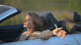 woman driving a car. convertible car. slow motion video. the wind blows the woman's hair. High quality Full HD video recording