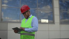 a man at a construction site in a red helmet. man looks at the tablet. slow motion video. a man works at a construction site. Full HD high quality video recording