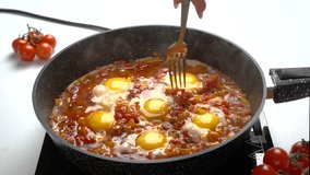 The cook stirs the eggs with a fork in the Frying Pan with Chopped Bell Peppers, Tomatoes and Onions. Recipe and cooking process for Shakshuka and Menemen. Step by step. twenty-fourth video