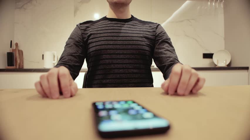 In front of a nervous man lies a smartphone in which he wants to play. Smartphone addiction concept. Waiting for an important phone call. Royalty-Free Stock Footage #1105022485