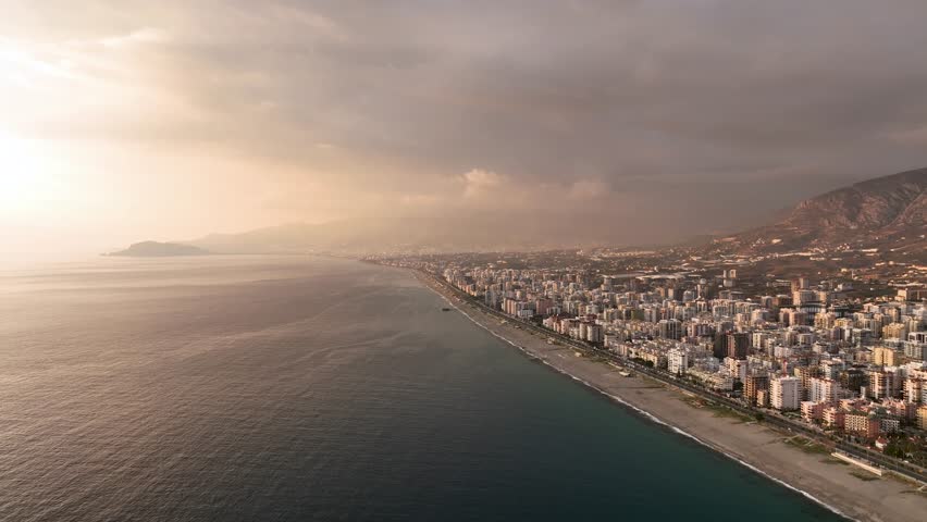 Twilight Elegance: Cinematic Drone Films the Exquisite Sunset in Soft Tones Above the Sea and Cityscape