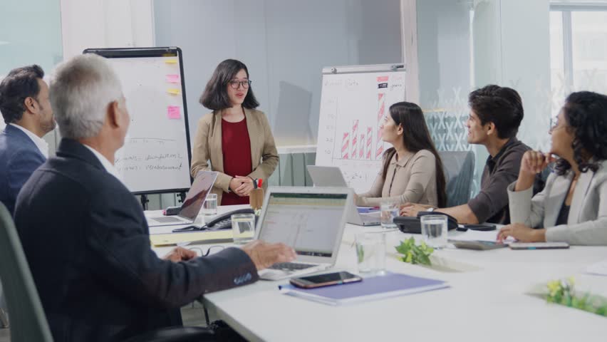 A young smiling modern corporate Asian girl or female office executive giving a presentation is appreciated or applauded by a diverse team of employees in a board room meeting in a start-up business - Powered by Shutterstock - Get 15% off with code: PIKWIZARD15