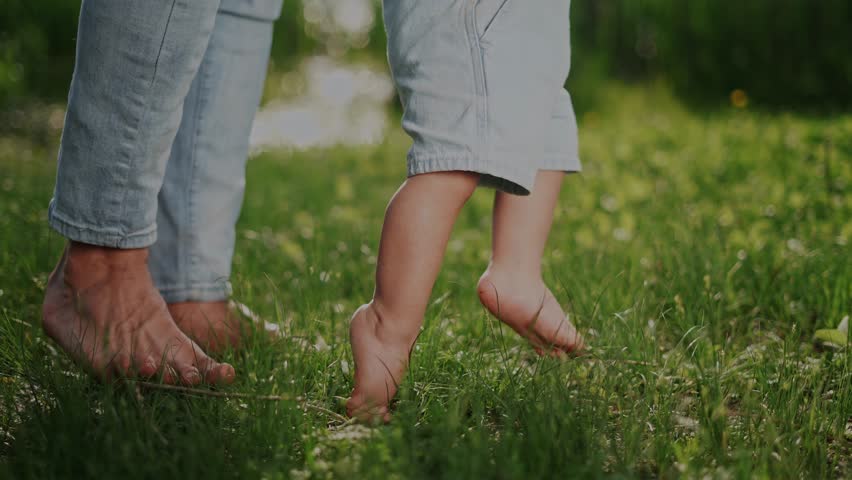 happy family. baby takes first steps in grass. father walk with son in nature. kid dream concept. baby takes first steps with mom. father and little son feet baby lifestyle close-up