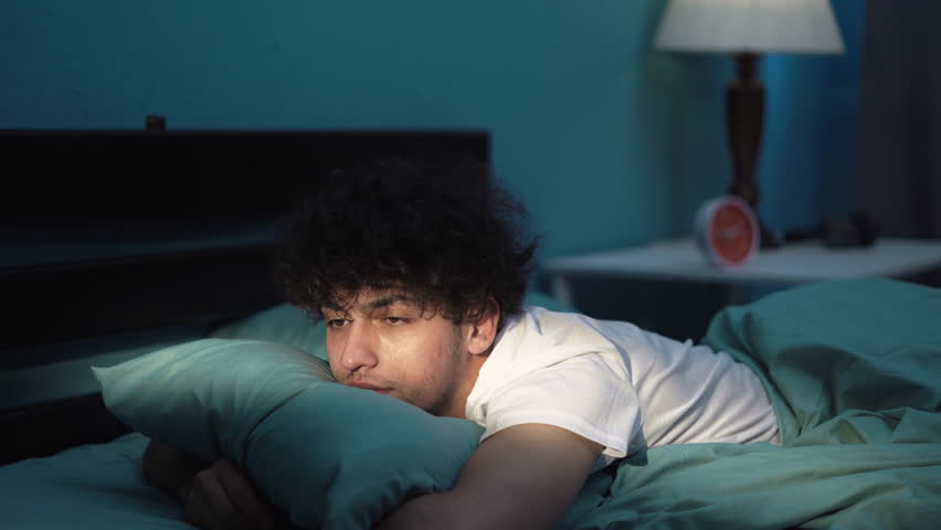 Young man lying in bed late at night trying to sleep suffering insomnia and sleeping disorder Royalty-Free Stock Footage #1105042537