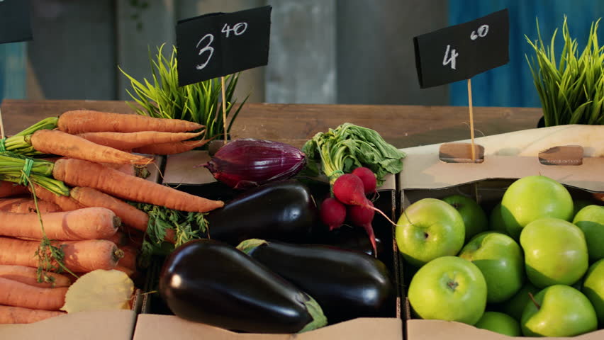 Various organic farmers market products from greenmarket, seasonal ripe fruits and vegetables on counter. Local bio fresh eggplants, carrots and juicy sweet apples in boxes. Organic farming.