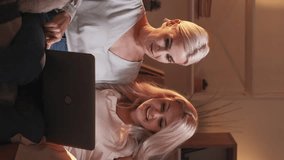 Vertical video. Family networking. Online evening. Watching computer. Joyful mother father and daughter watching laptop sitting sofa home interior.