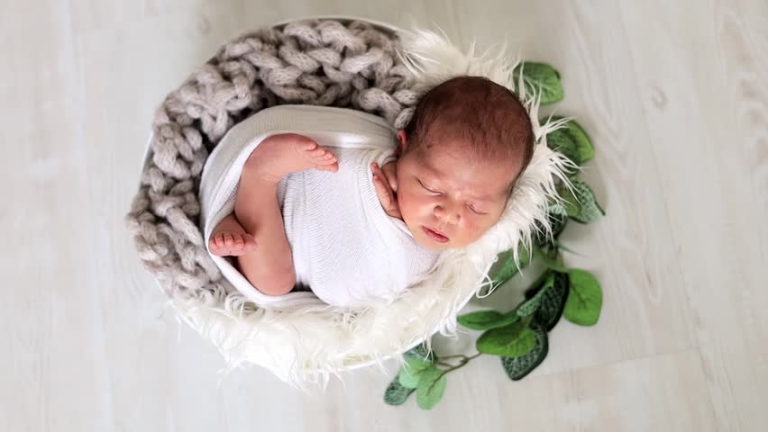close-up of a newborn baby girl in a diaper on a light background sleeping sweetly in a cute basket, the birth of a baby, a happy family