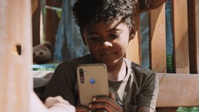 Closeup of African American elementary age boy meditatively watching something in smartphone