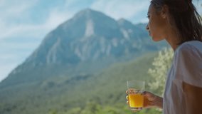 happy mixed race woman at sunny morning outdoors in mountain camping enjoying sunrise and drinking fresh orange juice. traveling, wellbeing and healthy nutrition concept. muontains ridge on background - Powered by Shutterstock - Get 15% off with code: PIKWIZARD15