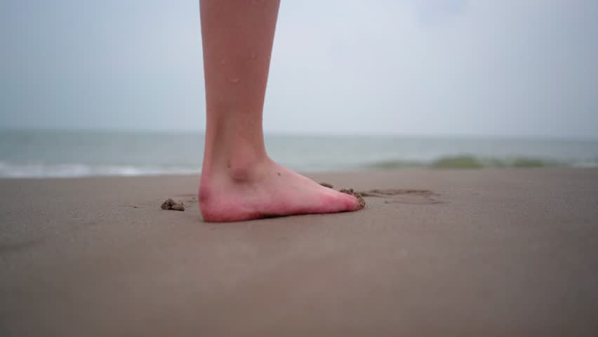 Close up of person bare feet walking at tropical beach. People playing barefoot at tropical beach. Having fun jumping in sea water on warm sunny day on seashore. Summer travel and vacation concept. | Shutterstock HD Video #1105053283
