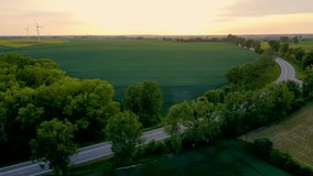 Aerial view of car and heavy trailer truck driving on beautiful countryside road at sunset. Cinematic drone shot video of flight over paved highway between agricultural fields
