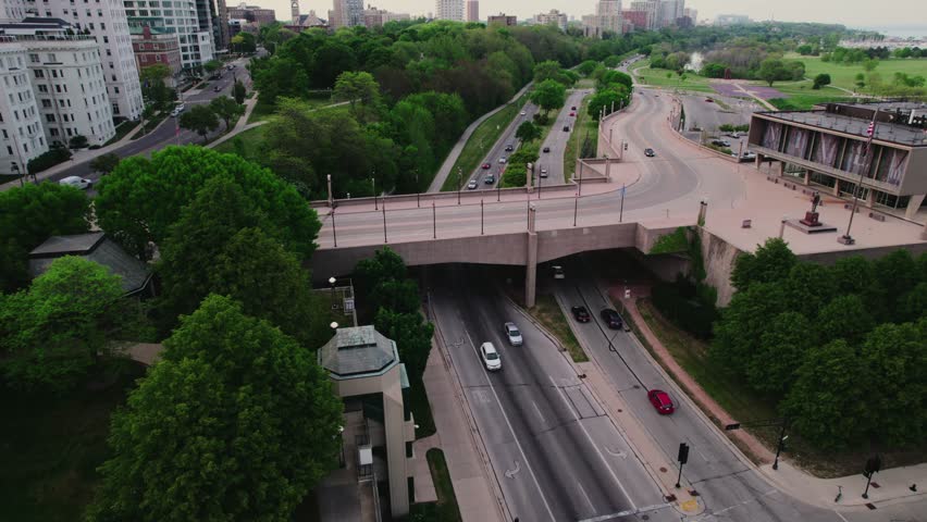 Milwaukee overpass bridge - E Mason St next to Juneau Park. Milwaukee Wisconsin downtown - aerial sunset. Summer with beautiful green trees. Drone pov 4k
