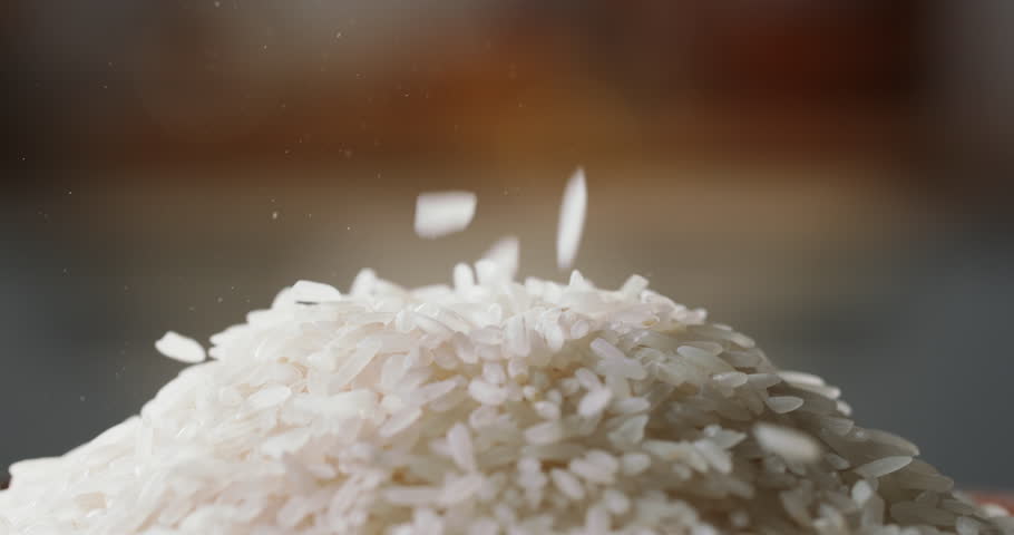 Raw rice poured pile, side view home kitchen blurred background Asian Chinese Thai Japanese Indian traditional cuisine. Natural vegetarian healthy food nutrition dieting
