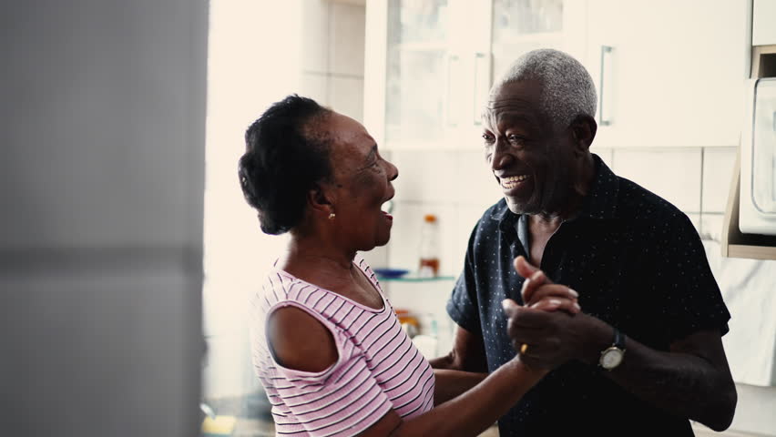 Happy Elderly couple dancing together in kitchen. A beautiful tender romantic moment between a black African American husband and wife Royalty-Free Stock Footage #1105064031