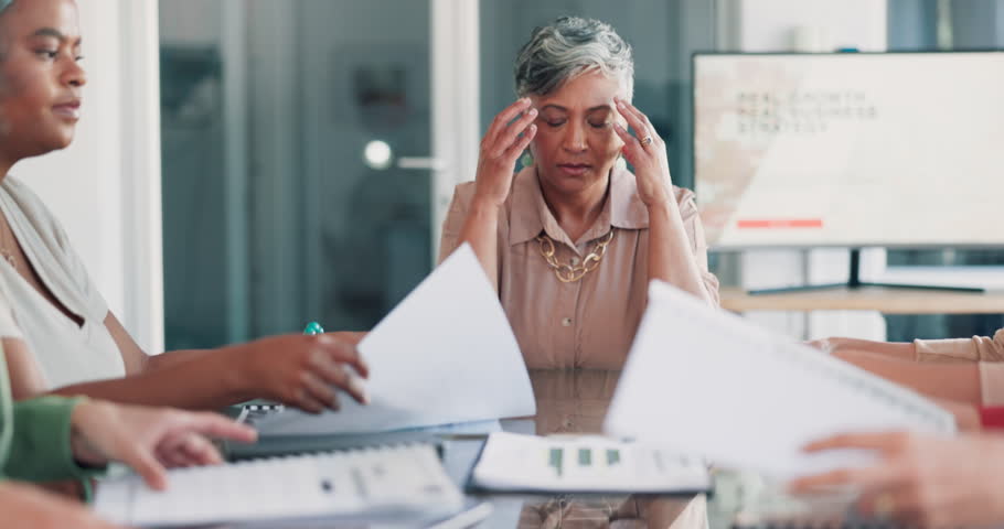 Headache, meeting and business woman stress, pain or anxiety, thinking of documents review. Burnout, fatigue or frustrated senior boss or manager in busy office with chaos of paperwork and team hands Royalty-Free Stock Footage #1105064833