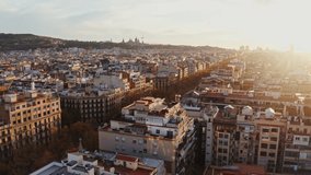 Bird's-eye view of residential areas, roads and sights of Barcelona in the rays of the rising sun, drone video